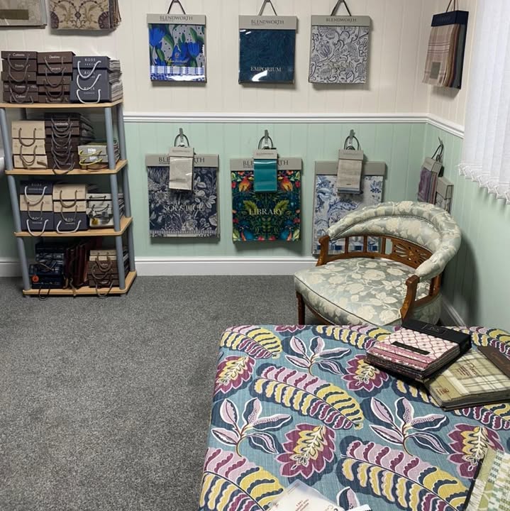 Our fabric showroom, with sample hangers and pattern books on the walls, a tub chair and a printed footstool