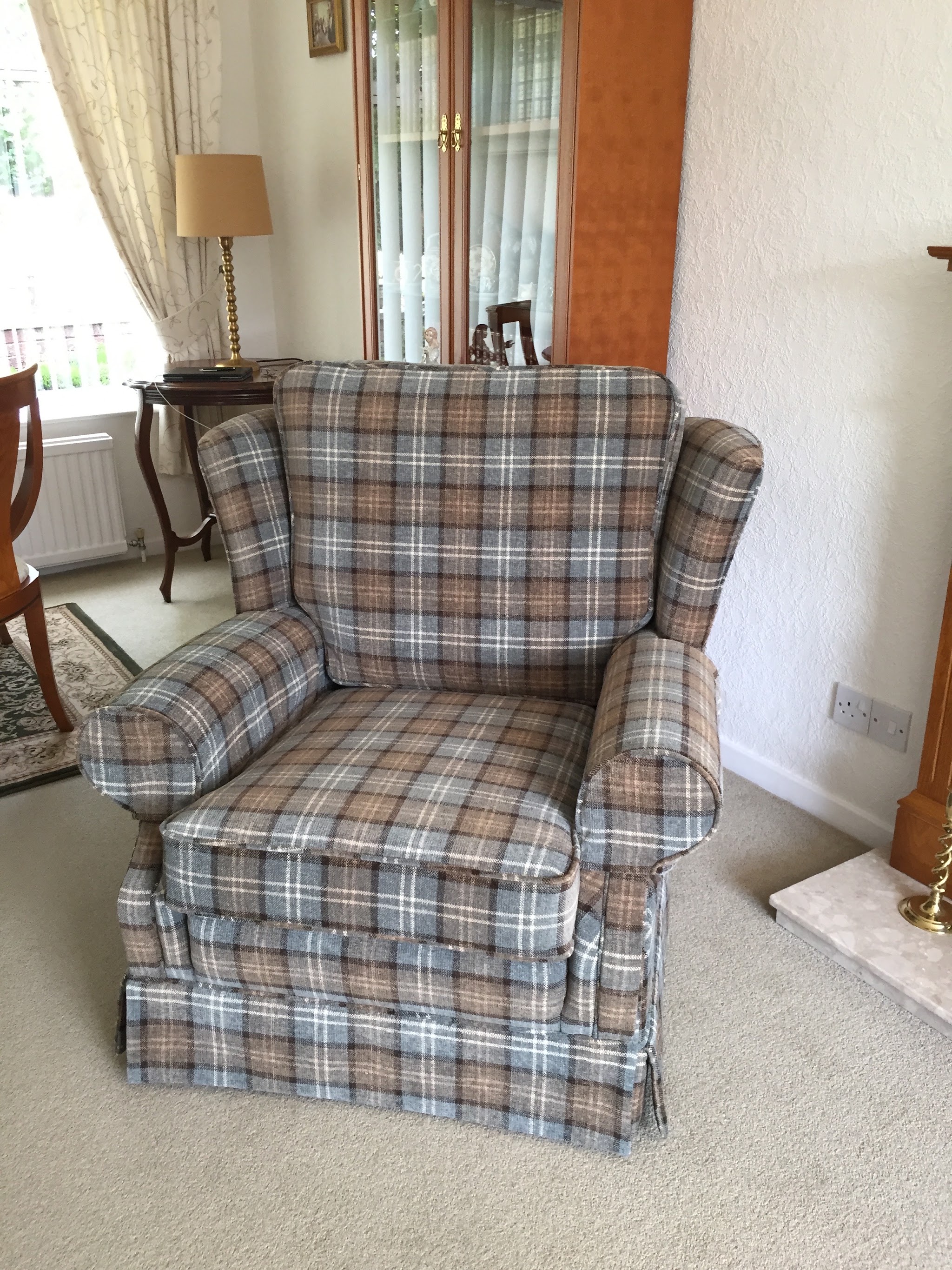 Armchair with a skirt in a grey and cream tartan, in a client's sitting room