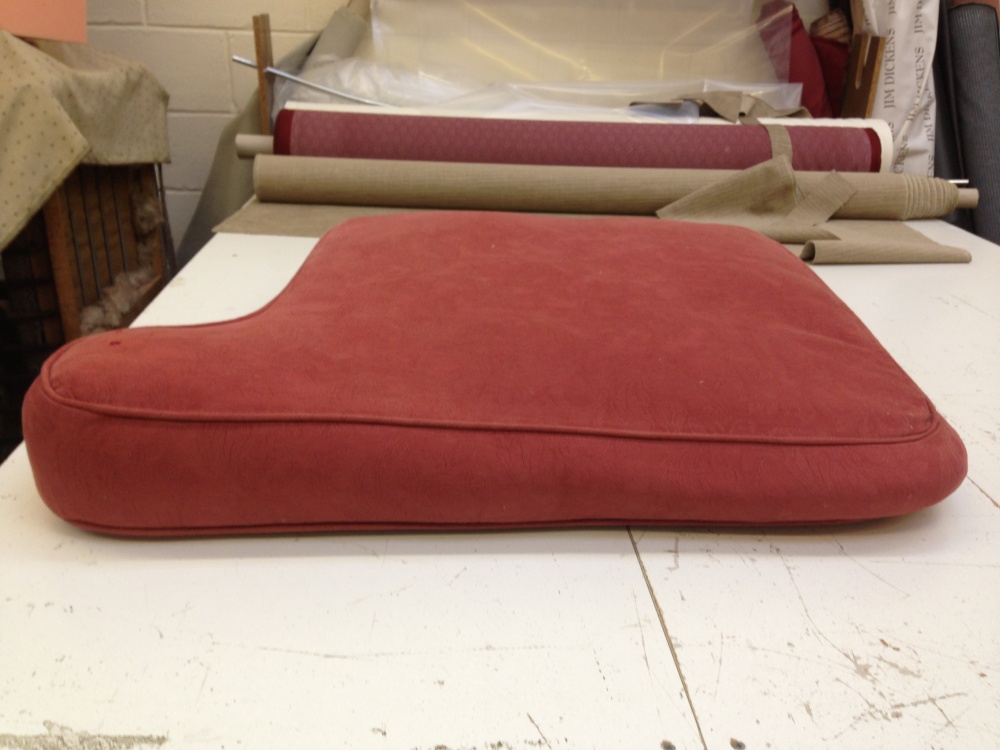 The finished red cushion with its new interior, on the workroom bench