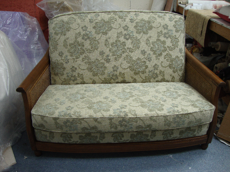 Cane-sided settee with removable covers in a pale floral fabric