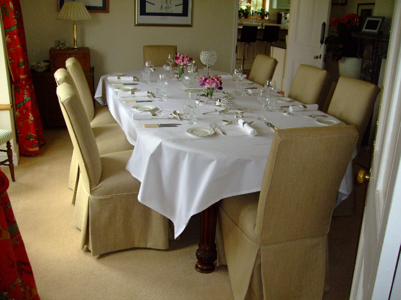 Dining room with chairs dressed in pale loose covers with skirted valances