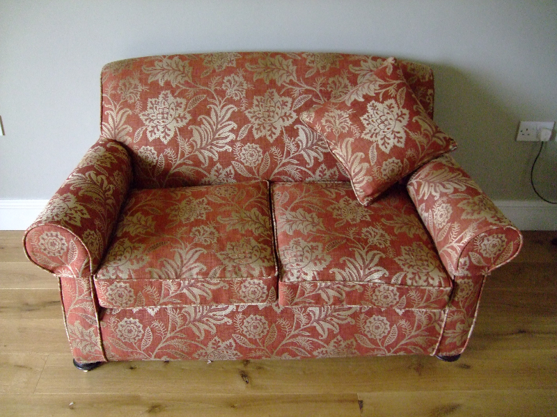 Two-seater sofa in a red and cream patterned loose cover