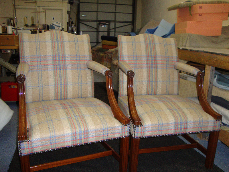 Pair of wooden-armed chairs in a pale plaid with a studded finish